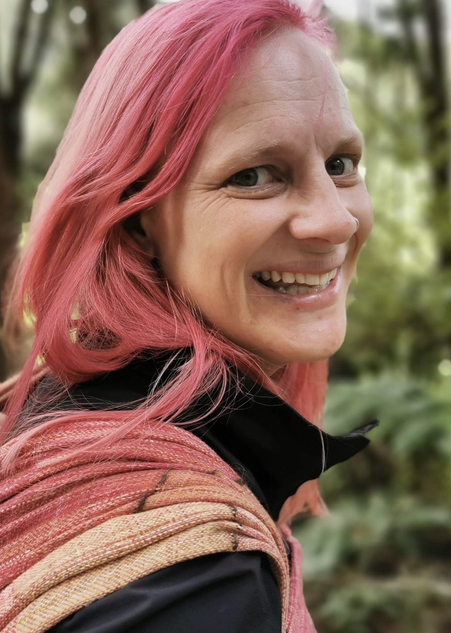 Image of Annelies Judson, pink-haired Pakeha woman who is probably in her mid-to-late 30s based on the lines beginning to form where she has frowned at too many bum jokes.